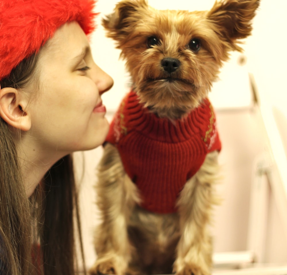 woman in red knit cap holding brown and black yorkshire terrier