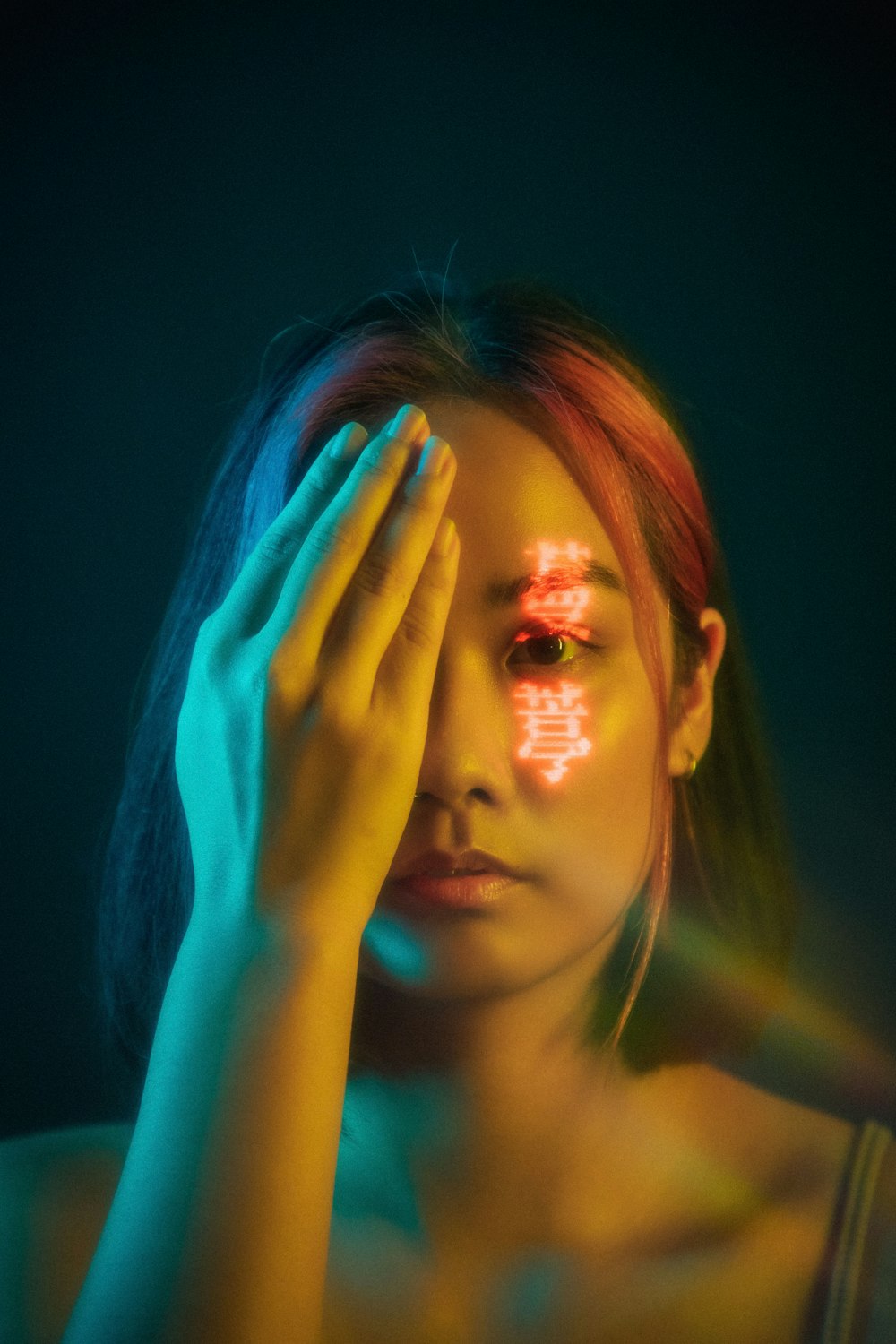 woman with blue hair covering her face with her hand