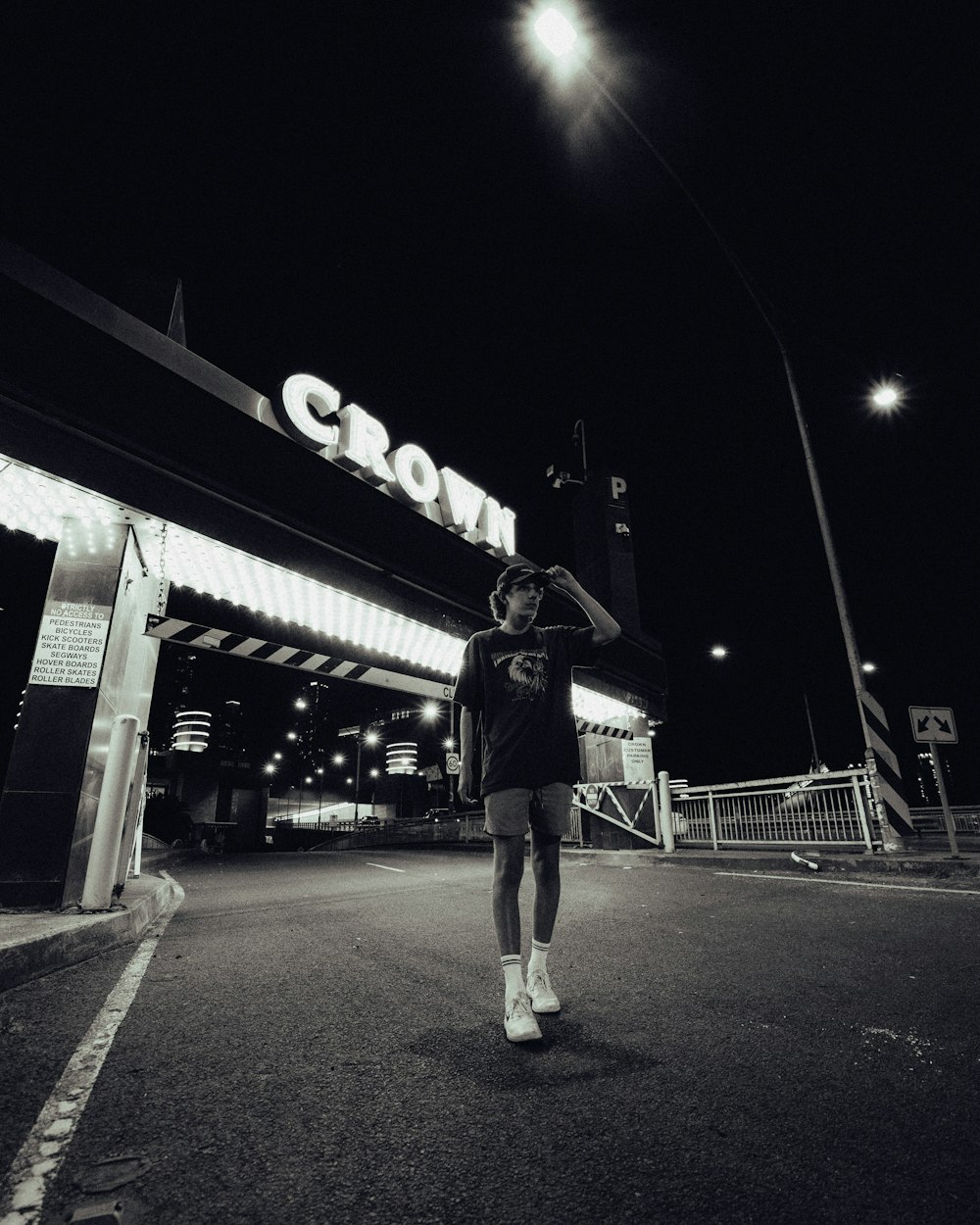 man in black jacket and black pants standing on gray concrete pavement during night time