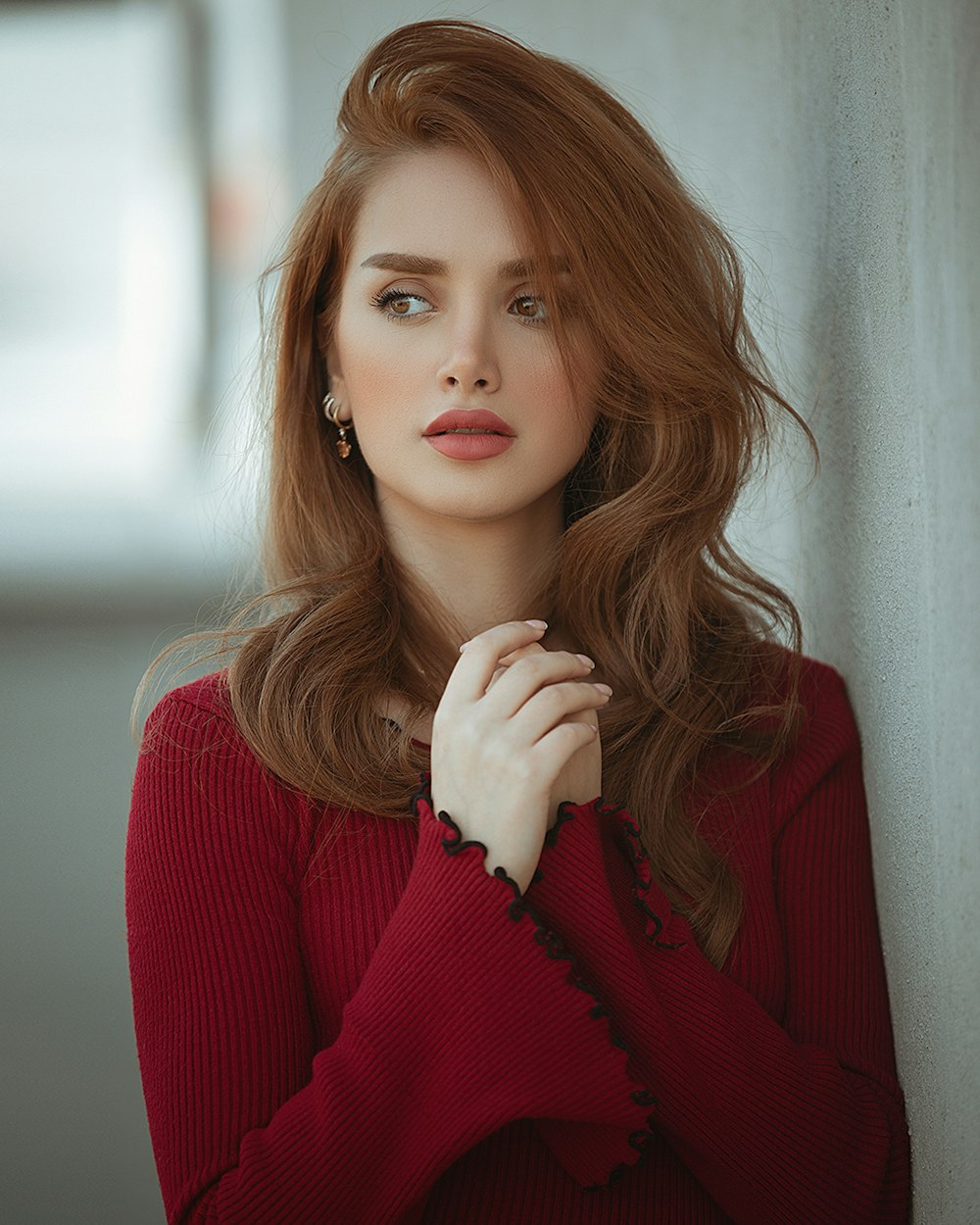 woman in red sweater holding her chin