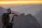 Smiling young traveler with a backpack enjoying a sunset view from a mountain lodge.