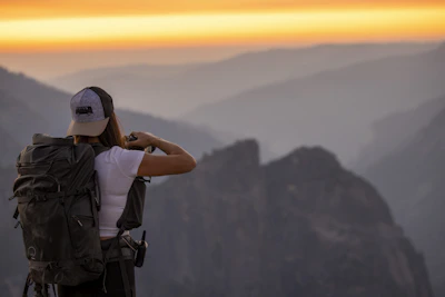 Happy travelers capturing memories at a stunning mountain viewpoint during golden hour.