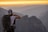 A traveler enjoying a scenic view with a backpack and a camera in hand.