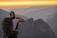 A traveler enjoying a scenic view with a backpack and a camera in hand.