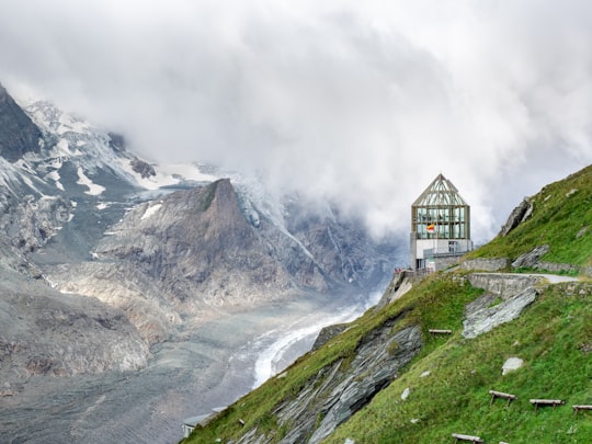 black and white house on green grass field near mountain under white clouds during daytime in Wilhelm Swarovski Beobachtungswarte Austria