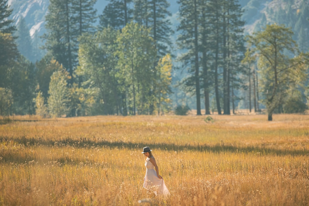 woman in white dress standing on brown grass field during daytime