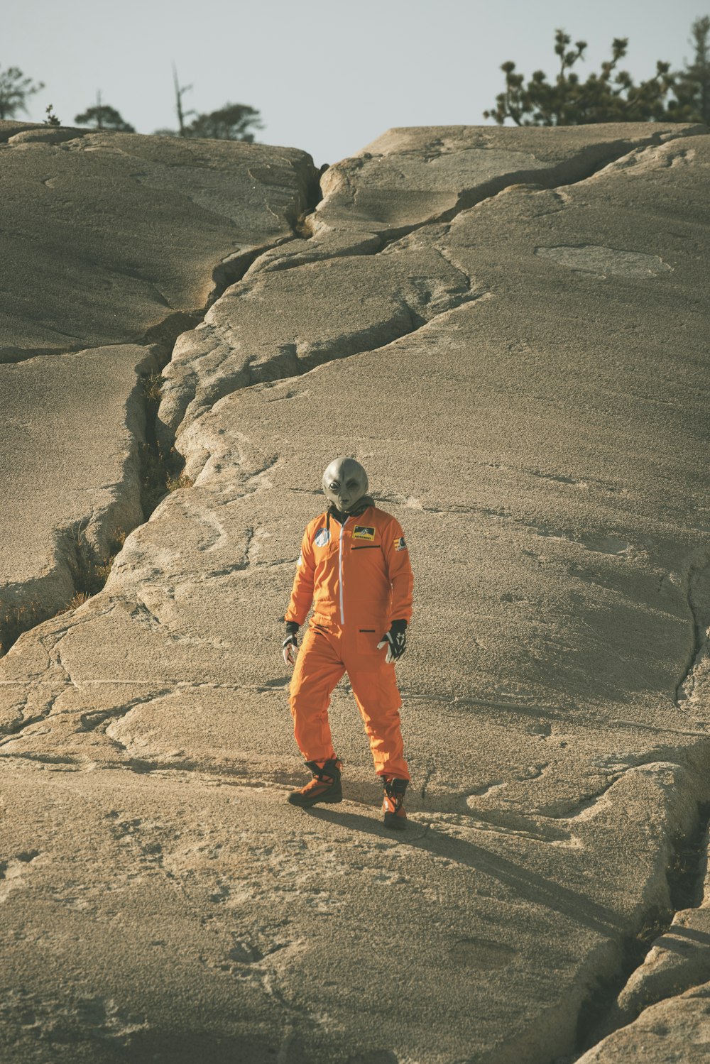 man in orange jacket and pants walking on brown sand during daytime