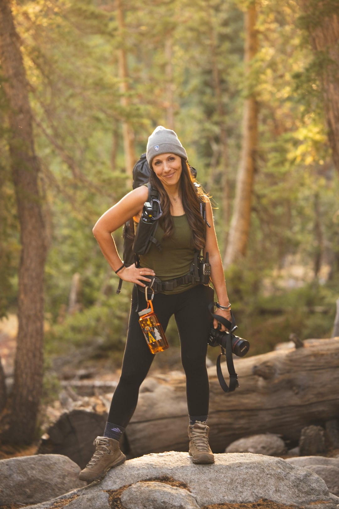 woman in brown t-shirt and white cap standing on brown wooden log during daytime