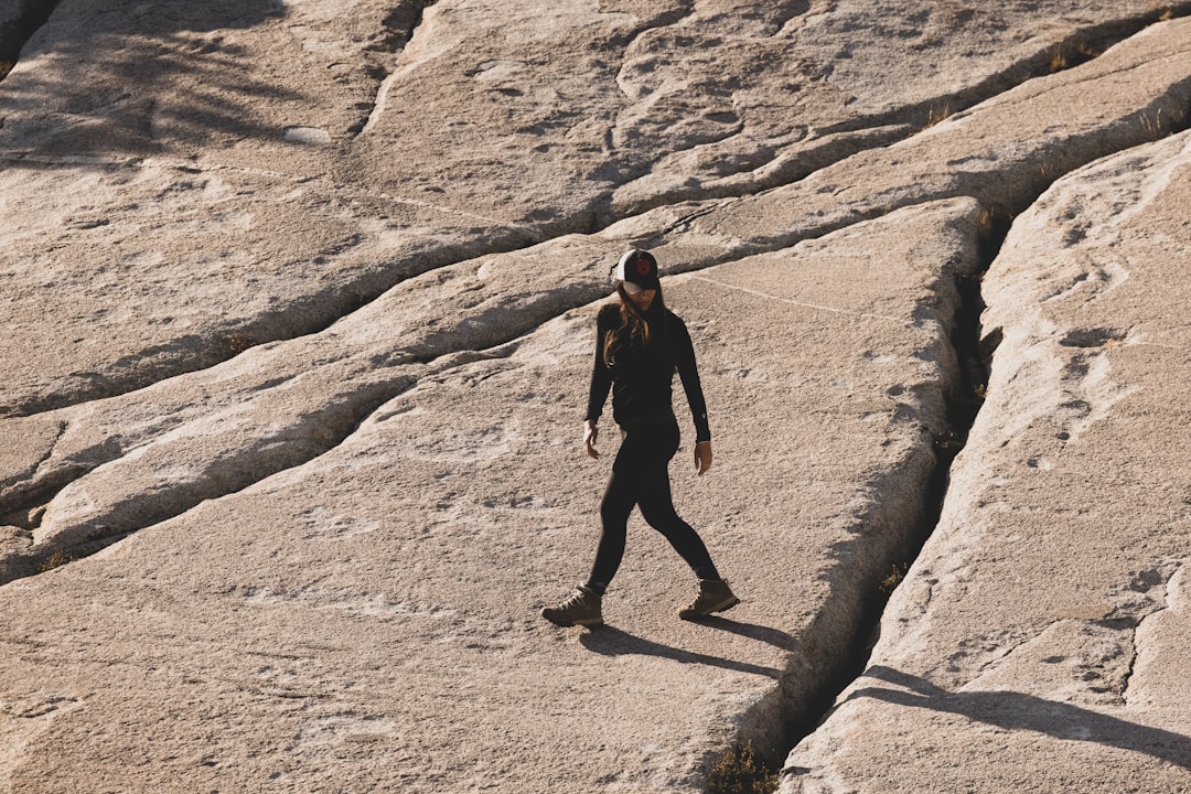 man in black jacket and black pants walking on brown rocky mountain during daytime