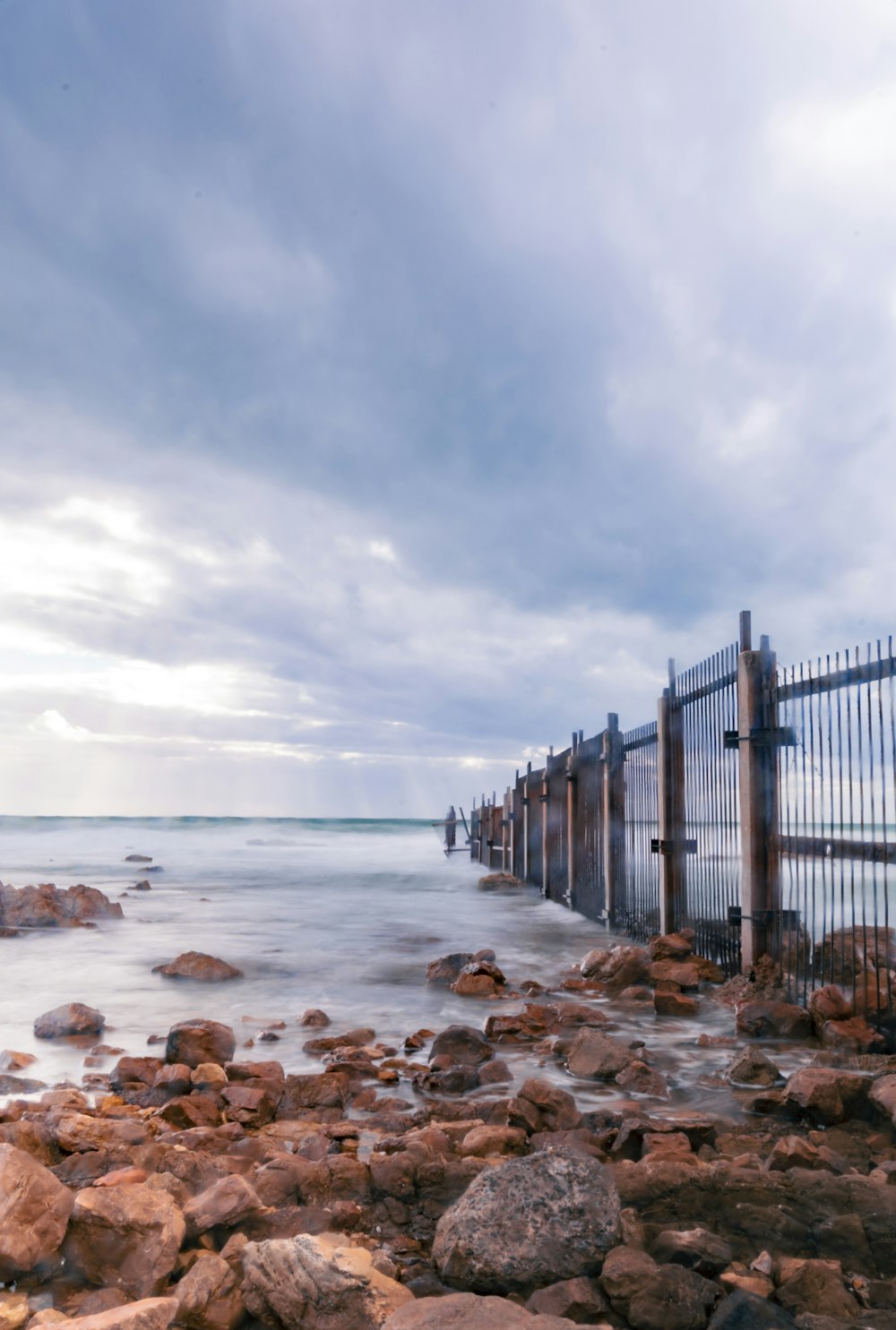 brown wooden fence on seashore during daytime