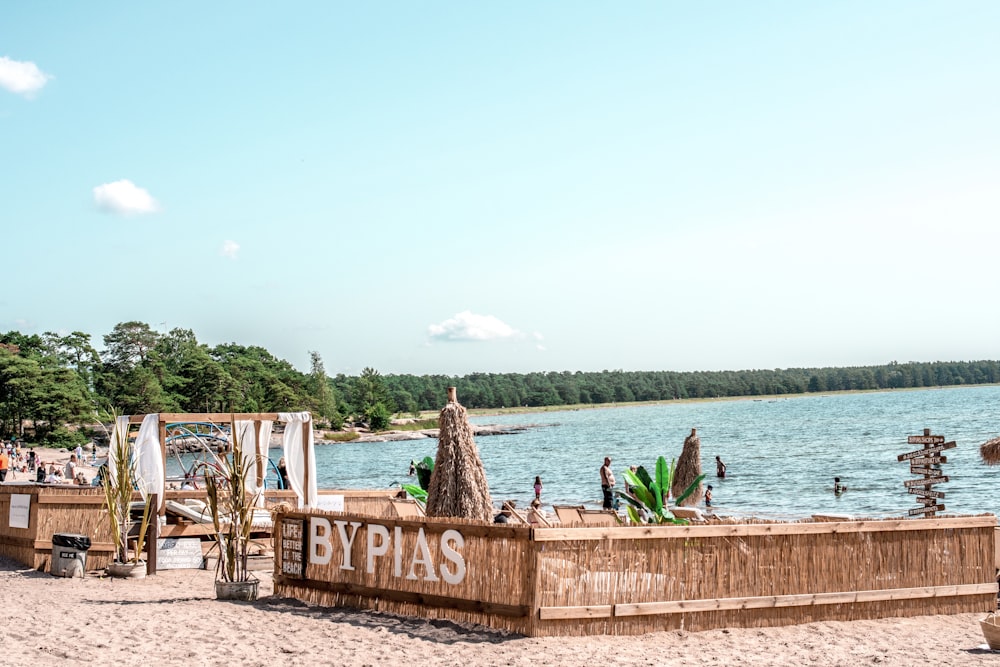 people sitting on brown wooden bench near body of water during daytime