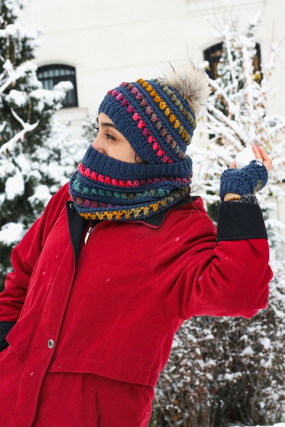 woman in red jacket and knit cap standing on snow covered ground during daytime