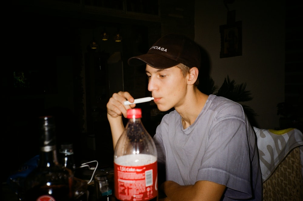 man in gray crew neck t-shirt drinking coca cola bottle