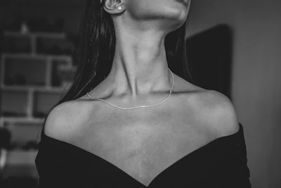 Elegant woman wearing a fine silver necklace, captured in natural light with a muted palette.