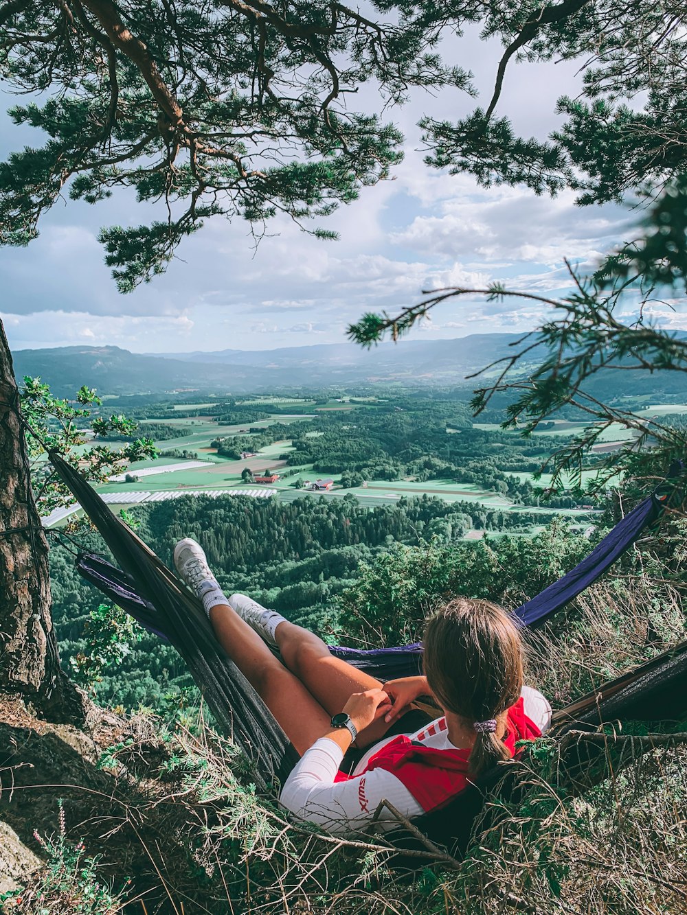 woman in red tank top sitting on blue hammock