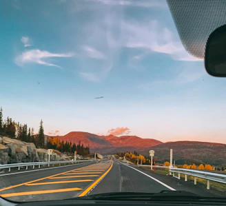 Sunset view from a highway stretch with distant mountains framing the horizon, inviting endless travel.