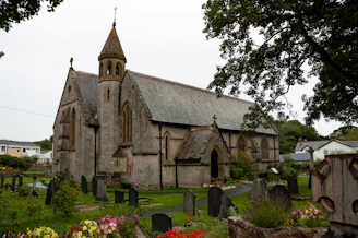 A charming old stone church with stained glass windows surrounded by summer greenery.