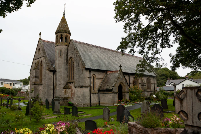 A charming old stone church with stained glass windows surrounded by summer greenery.