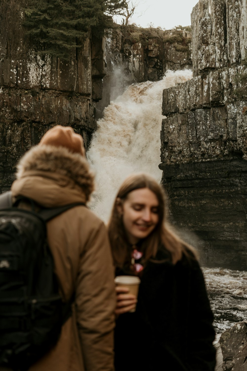 2 women standing near waterfalls during daytime