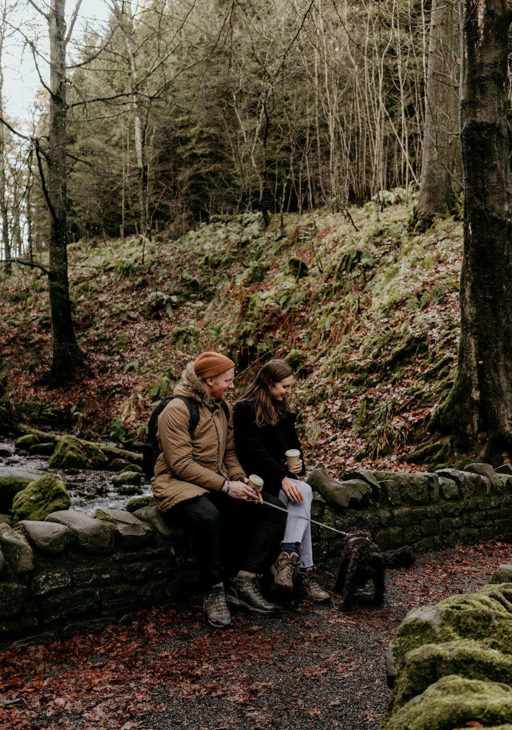 man and woman sitting on rock in the forest during daytime
