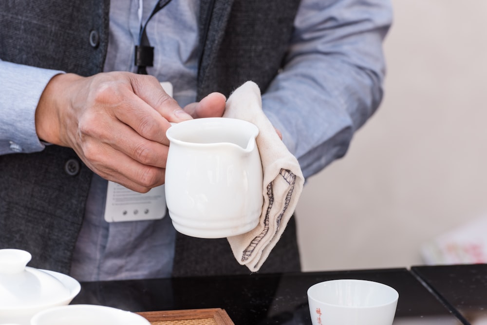 person holding white ceramic teacup