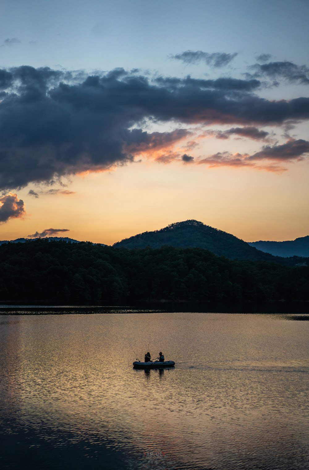 夕暮れ時の湖でボートに乗る人々のシルエット