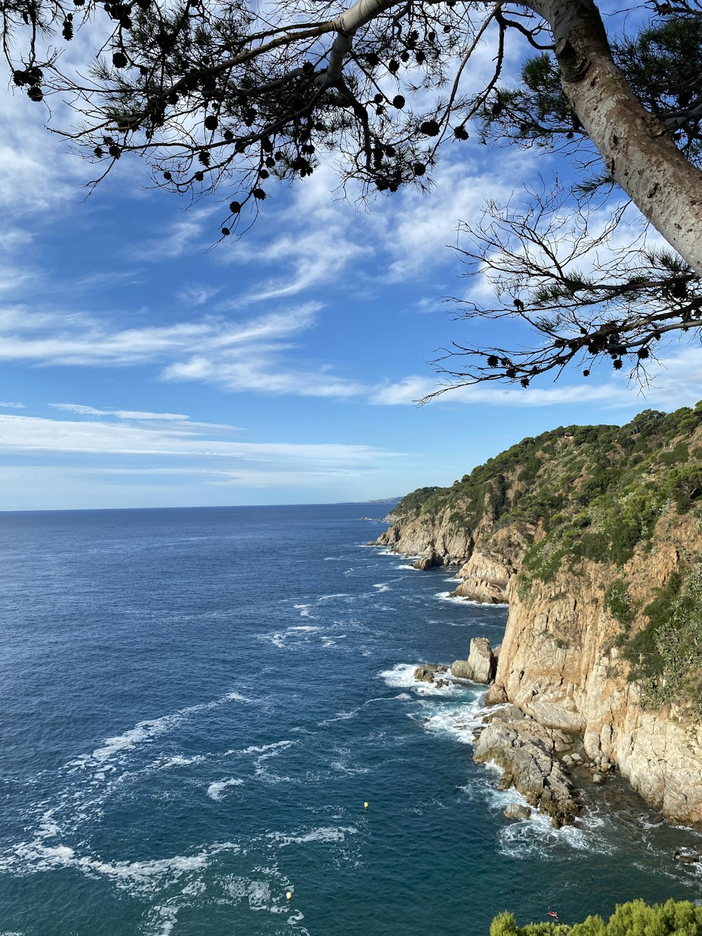 brown rocky mountain beside blue sea under blue sky during daytime