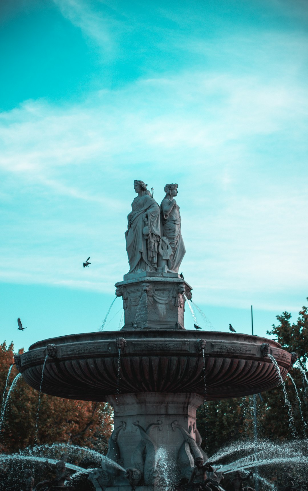 statue of man on water fountain under blue sky during daytime