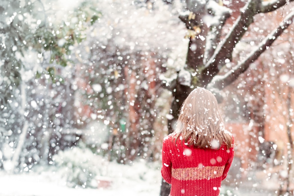 girl in red and white striped long sleeve shirt standing in front of snow covered trees