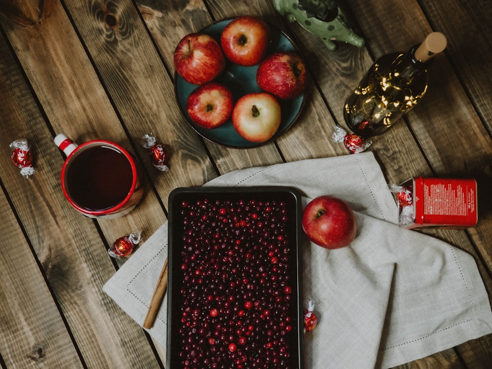 red apple fruit on black tray beside red ceramic mug
