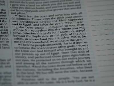 The image contains a close-up section of a book, likely a religious text, with slightly blurred and highlighted text emphasizing the words 'Lord', 'serve', and 'choose'. The text appears structured in paragraphs with some sections indented.