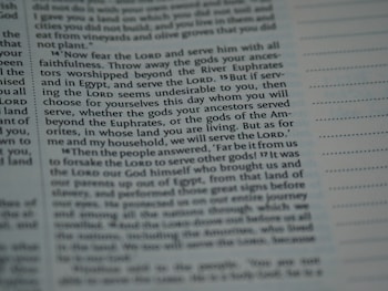 The image contains a close-up section of a book, likely a religious text, with slightly blurred and highlighted text emphasizing the words 'Lord', 'serve', and 'choose'. The text appears structured in paragraphs with some sections indented.