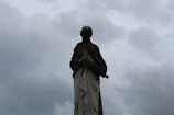 A weathered statue half-buried in sand under a twilight sky.