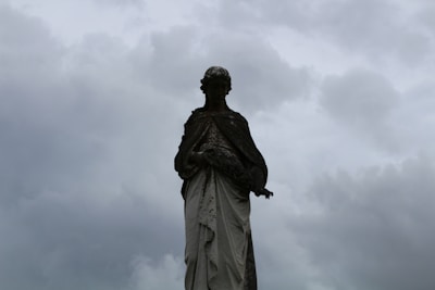 A weathered statue half-buried in sand under a twilight sky.