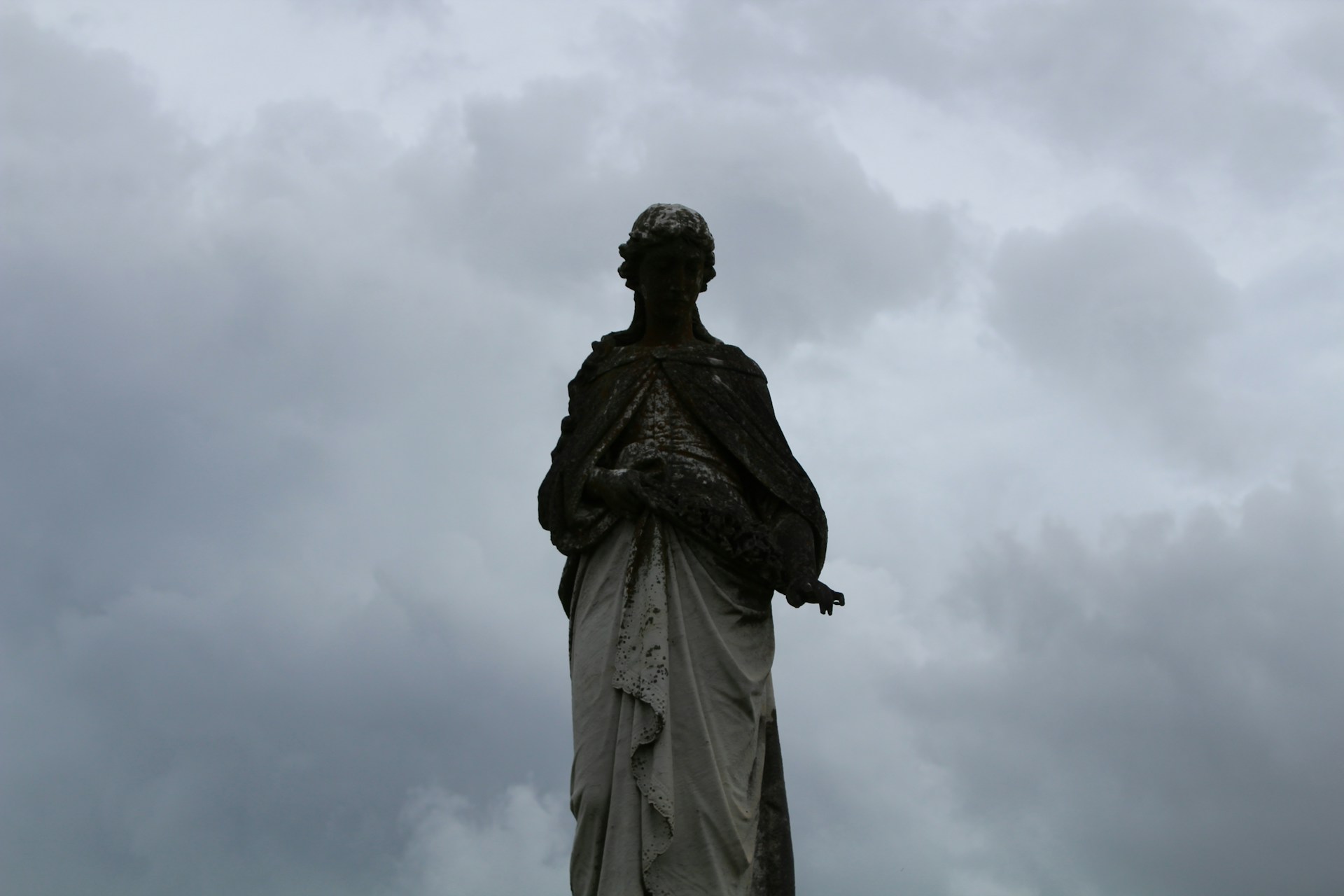 A weathered statue of a forgotten deity standing guard over a crumbling temple at twilight.