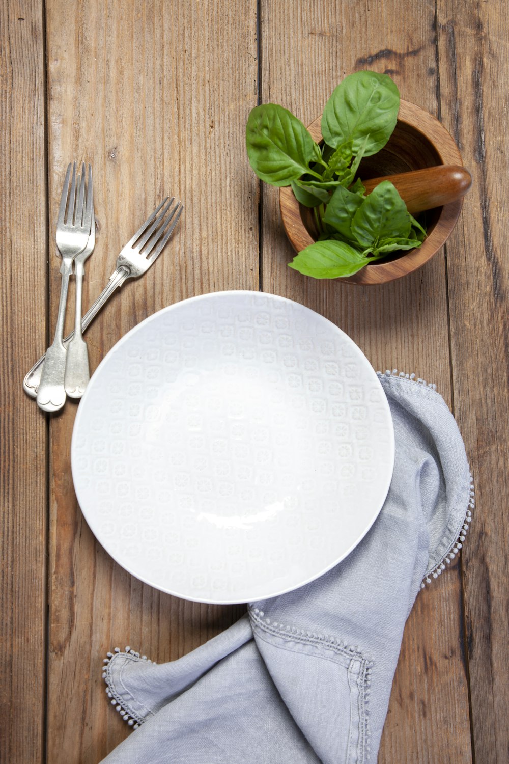 Plato de cerámica blanca junto al tenedor de acero inoxidable y el cuchillo de pan