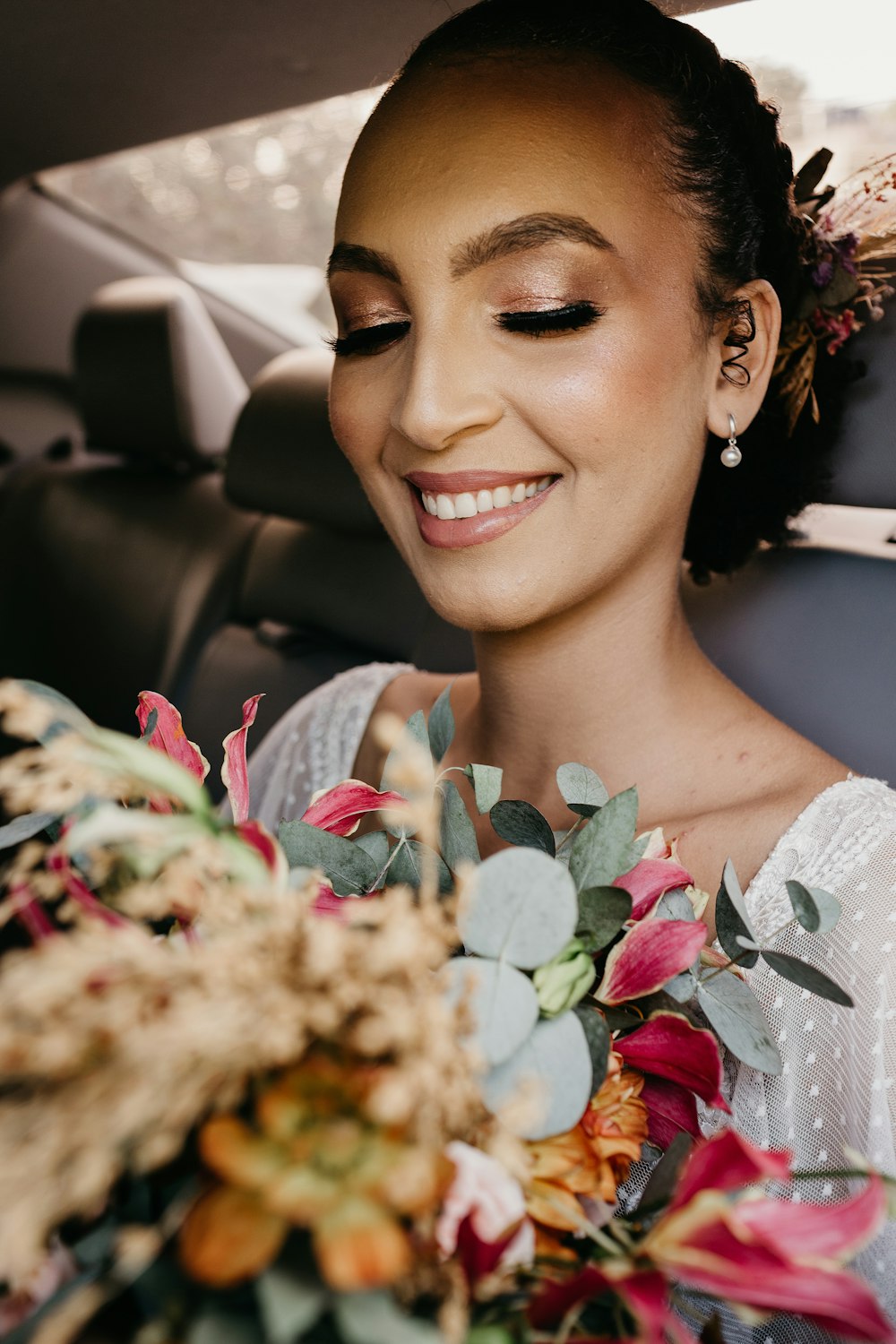 smiling woman in white and red floral shirt sitting inside car