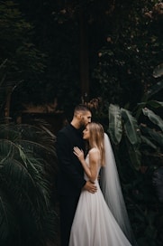 man and woman kissing near green plants during daytime