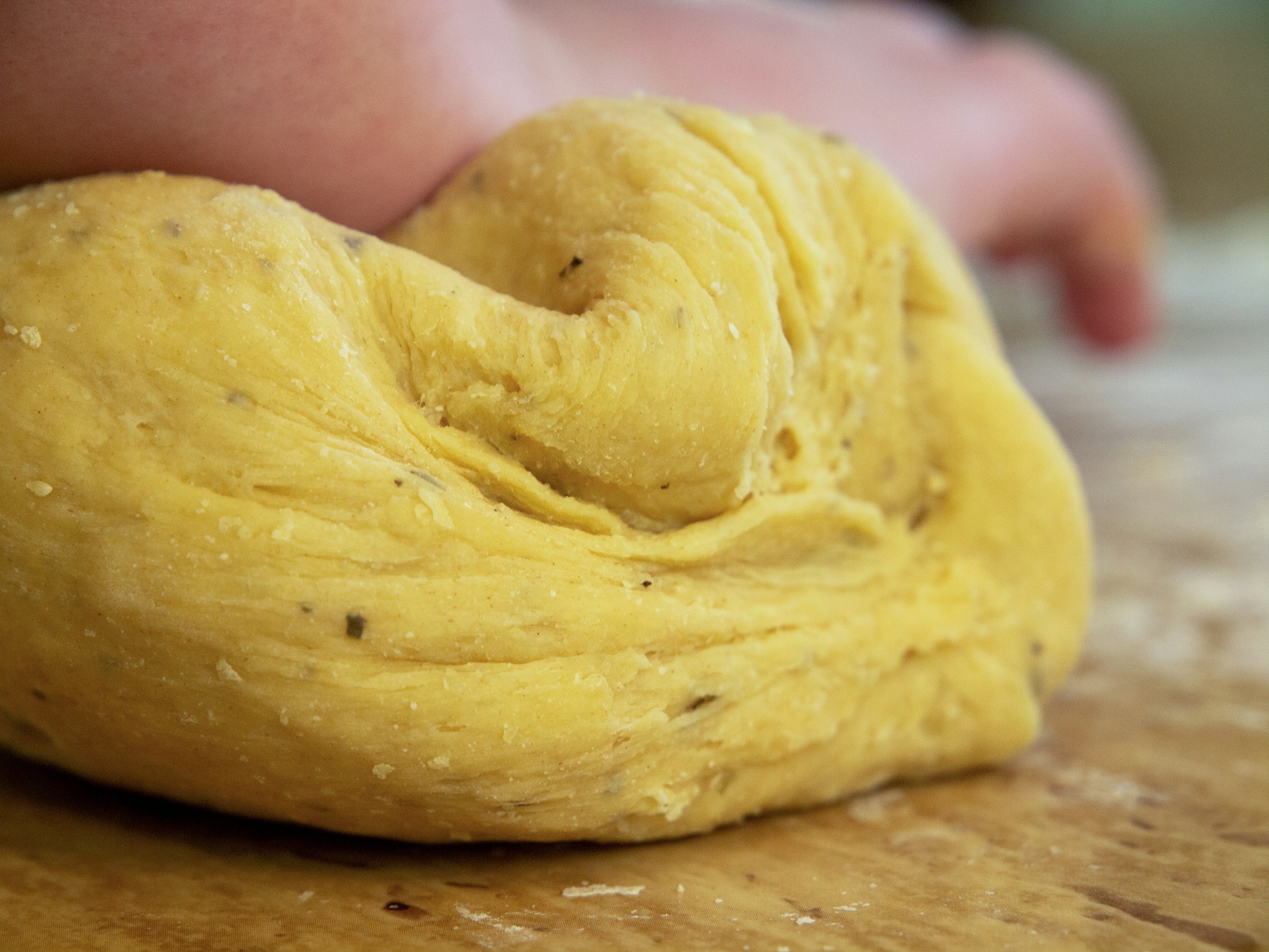 person holding dough on brown wooden table