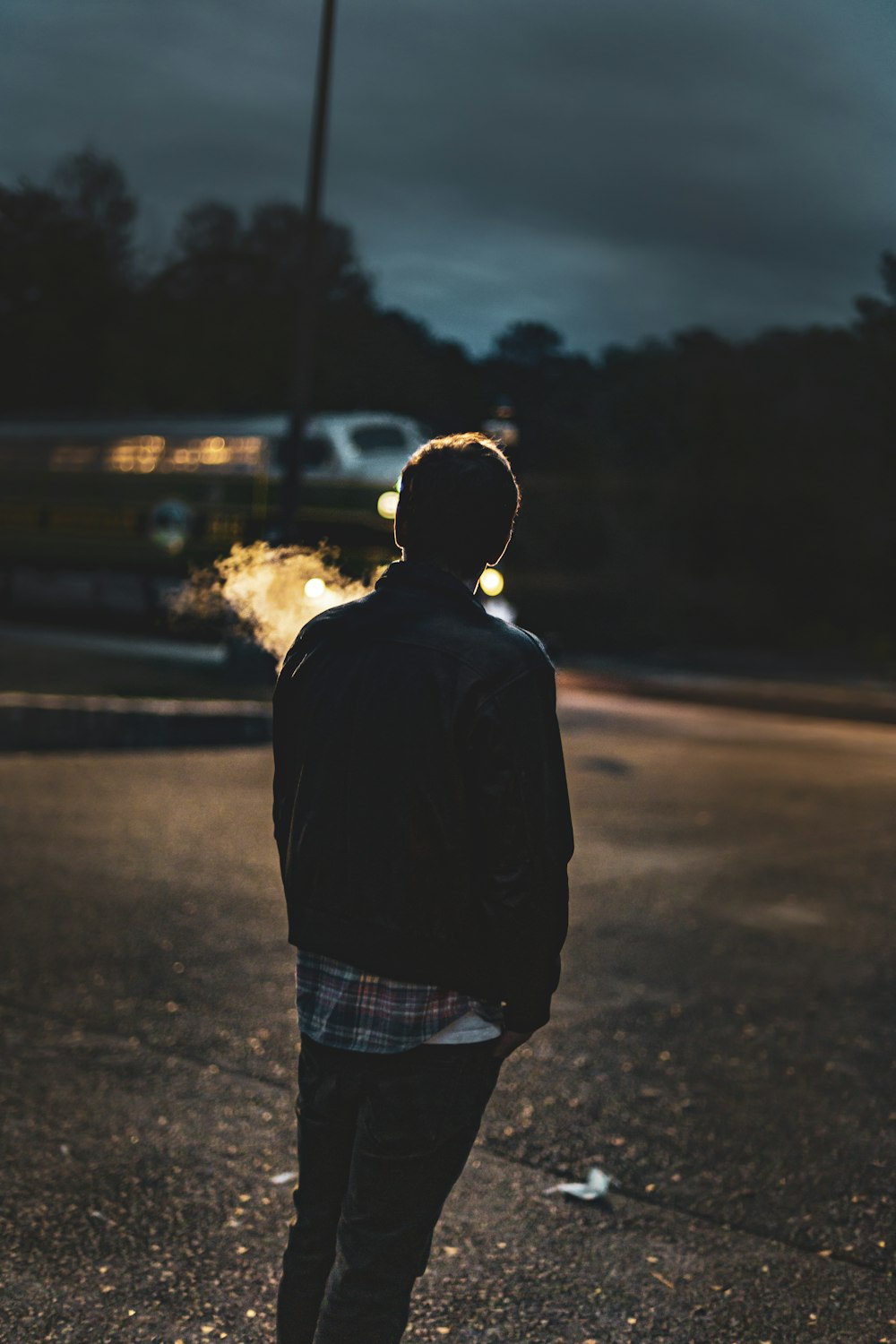 man in black jacket standing on road during sunset