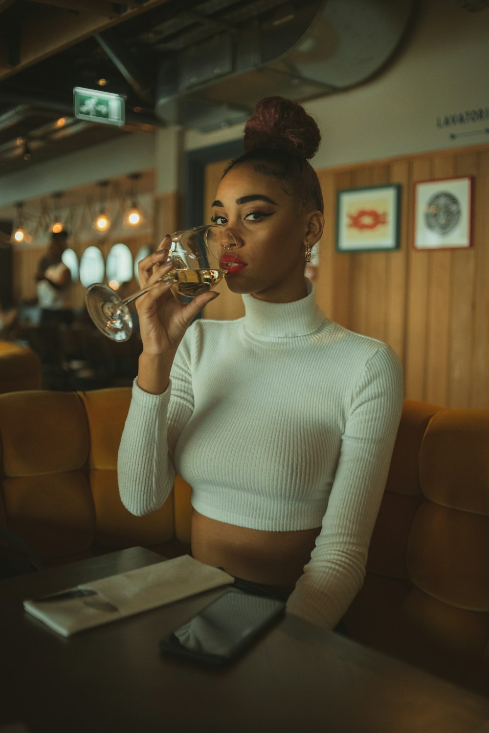 woman in white turtleneck sweater holding clear drinking glass