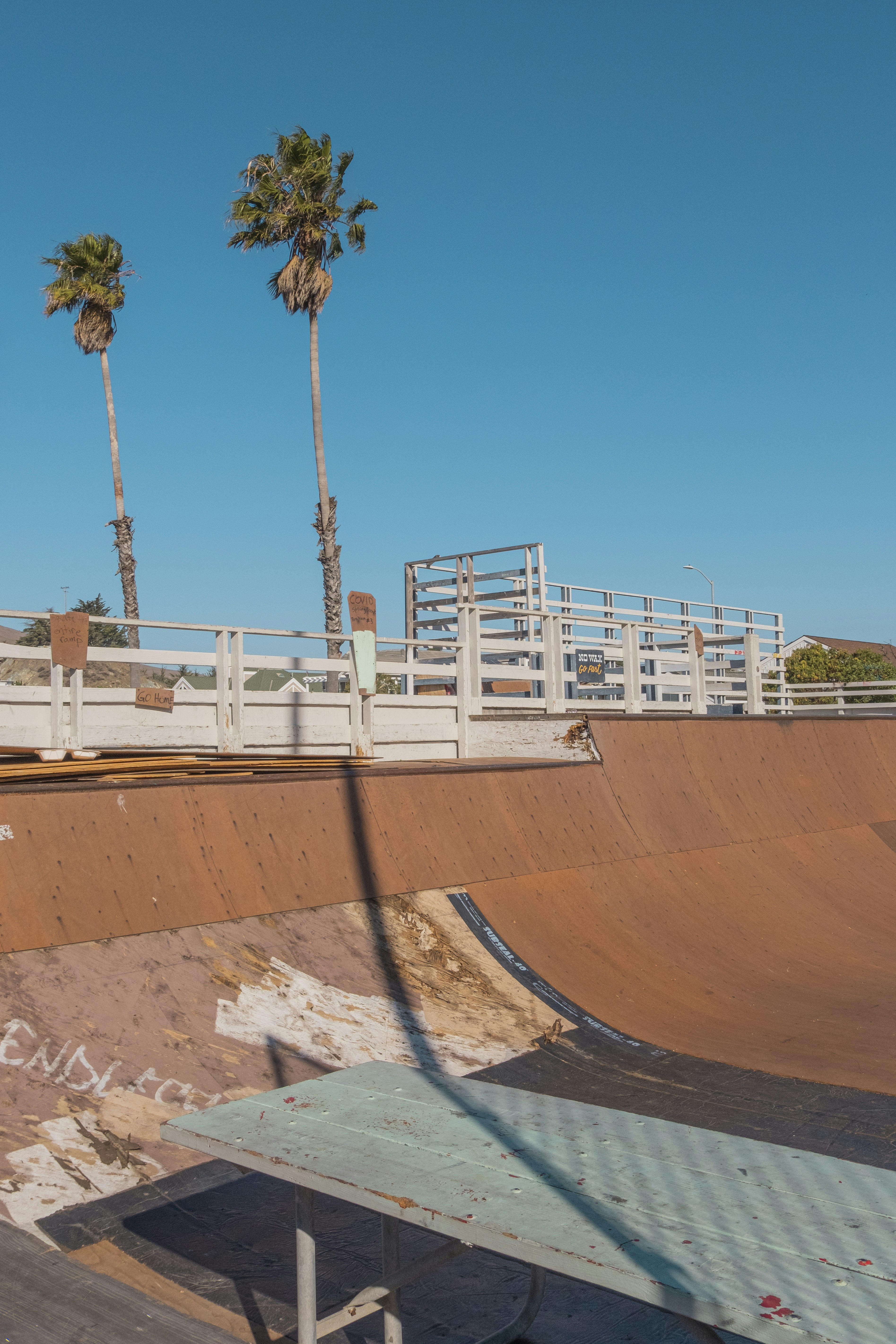 Clôture en bois blanc et brun près d’un bâtiment en béton blanc pendant la journée