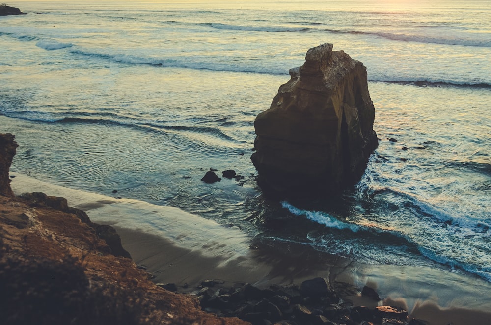 brown rock formation on sea water during daytime