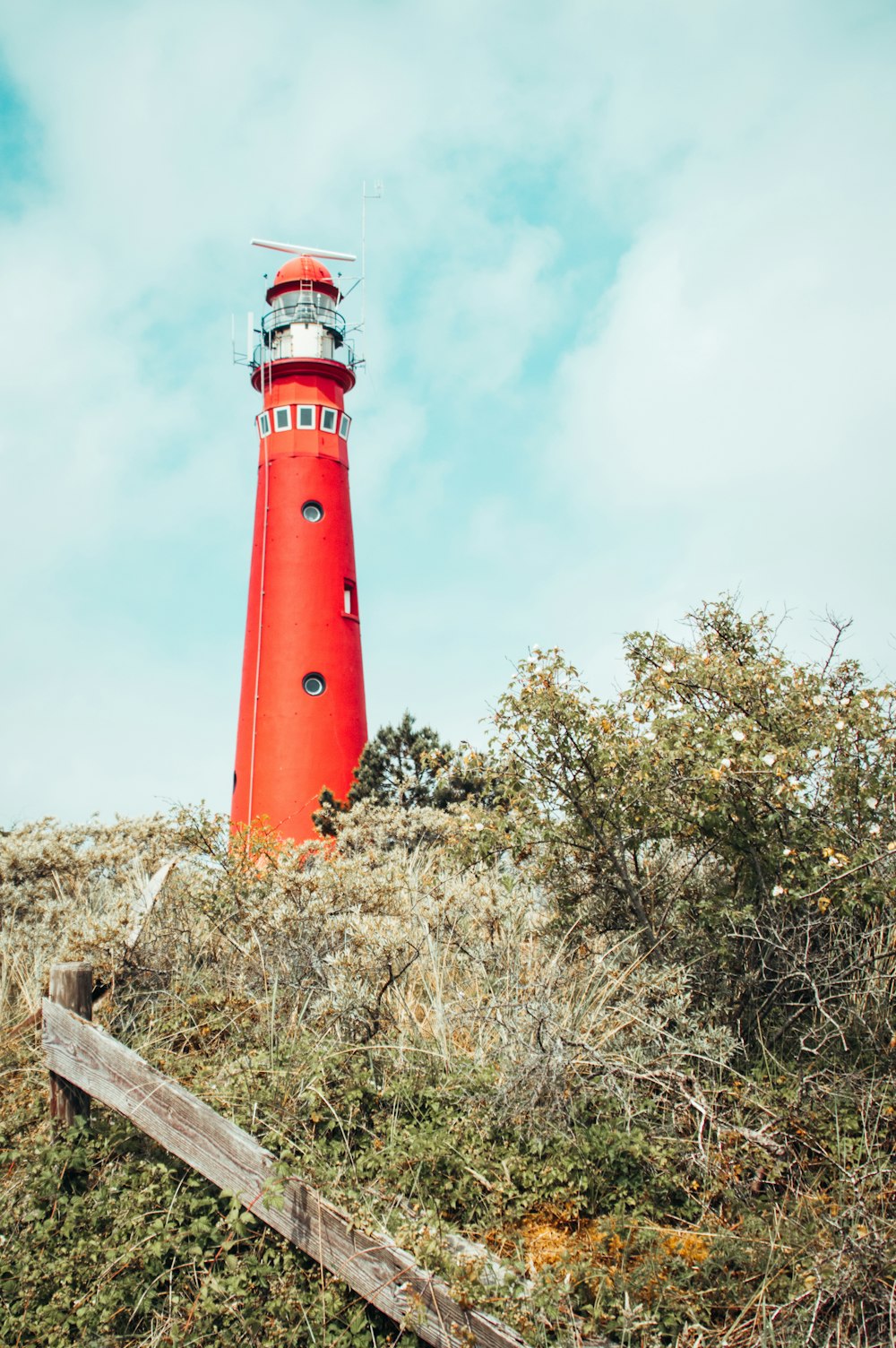 red and white lighthouse under white clouds during daytime