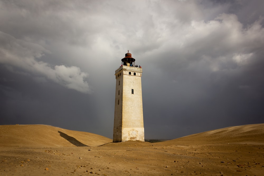 Weißer Leuchtturm tagsüber unter bewölktem Himmel