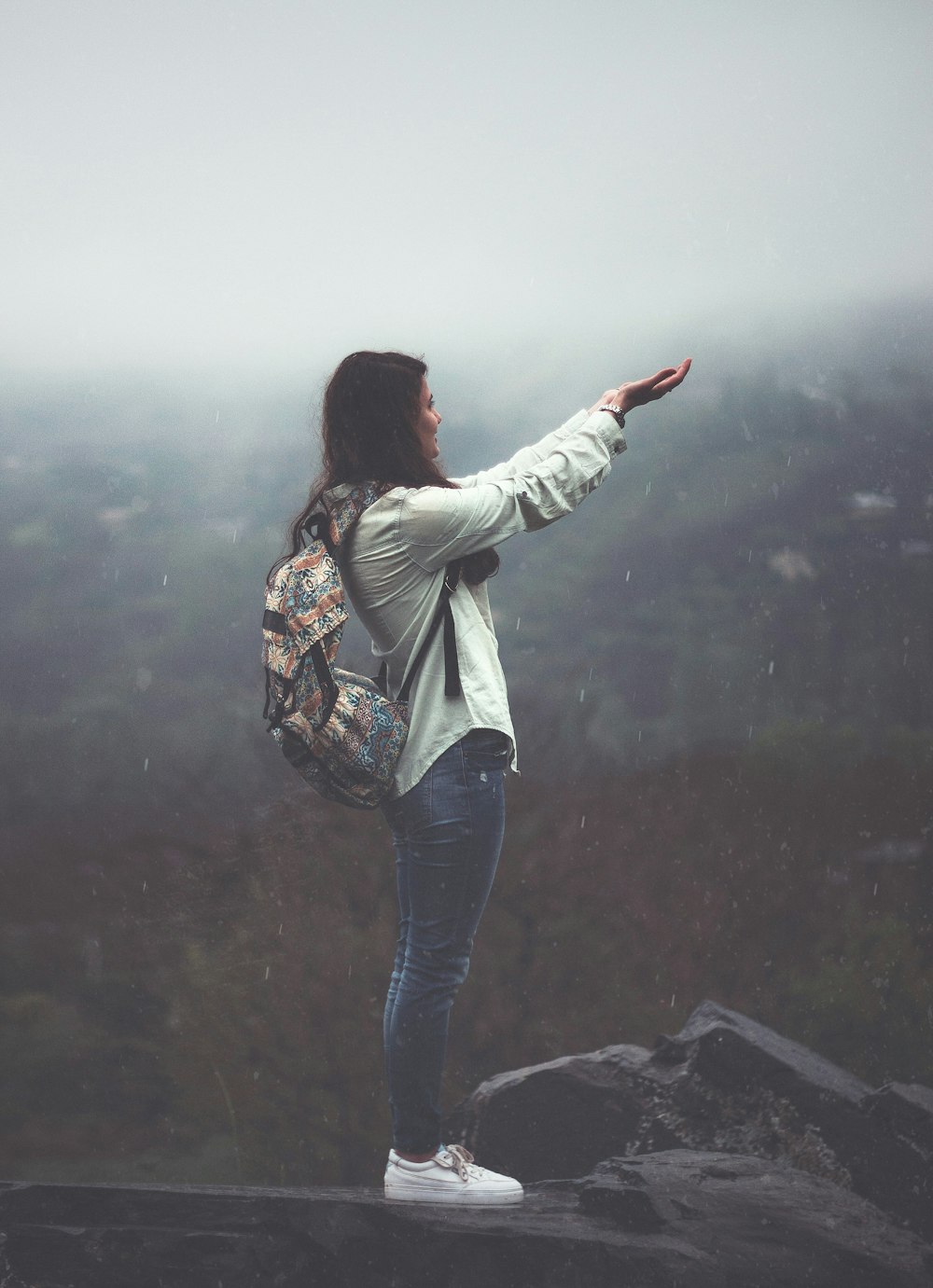 woman in white long sleeve shirt and blue denim jeans standing on gray concrete floor