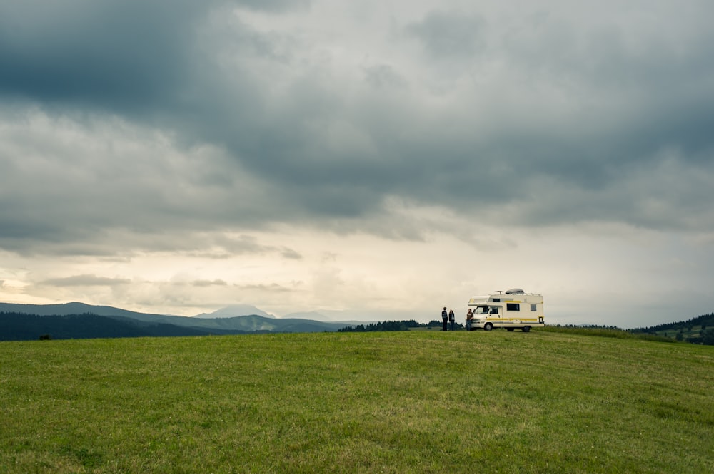 white van on green grass field under cloudy sky during daytime