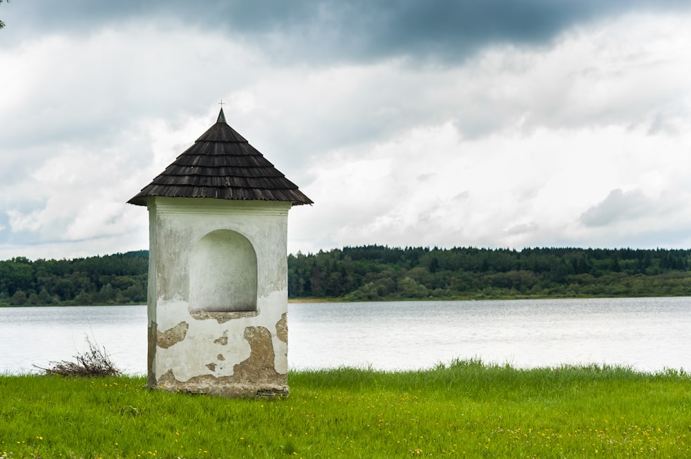 Maison en béton brun et blanc près d’un champ d’herbe verte et d’un plan d’eau pendant la journée