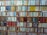 The image displays a collection of neatly arranged pencils or similar items, stored on shelves. Each shelf holds rows of colorful, intricately patterned items, showcasing a wide variety of designs and colors. The shelves are wooden and the items are organized and aligned in a uniform manner.