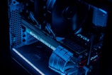 A detailed view of a computer's interior showcasing components such as a graphics card, cooling fans, and neatly arranged cables. The image features low lighting with a prominent blue LED glow highlighting the hardware.